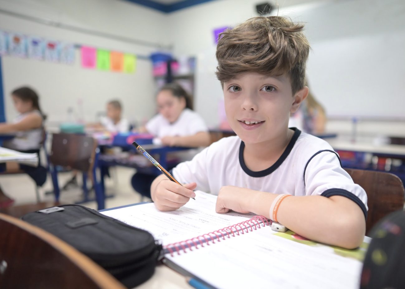 Aluno do Ensino Fundamental I escrevendo no caderno